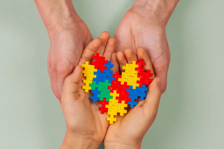 Autism-Clinic Two pairs of hands hold a puzzle in the shape of a heart. Get treatment for Autism from Discovery Health Healing Center in Green Bay.