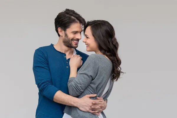 Erectile-Dysfunction-Doctor A man in a blue shirt embracing a woman in a gray shirt smiles due to his successful erectile dysfunction care from Discovery Health Healing Center in Green Bay.