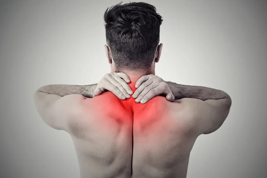 Fibromyalgia-Doctor An image from behind of a man suffering from Fibromyalgia rubbing an area illustrated red with pain in his shoulders and neck . Get fibromyalgia treatment from Discovery Health Healing Center in Green Bay.