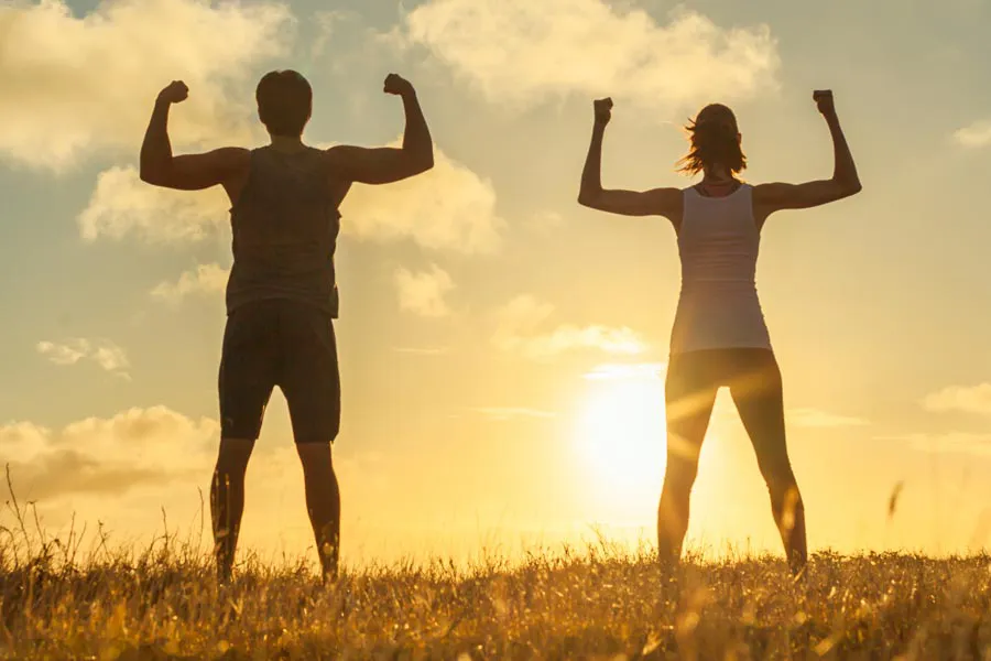 Immune-Support-Clinic A healthy couple stand in a field flexing their muscles, silhouetted by the sunset. Get Immune Support treatment from Discovery Health Healing Center in Green Bay.