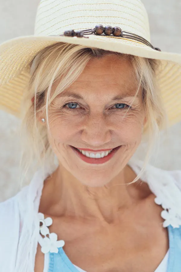 Menopause-Treatment A beautiful, smiling older woman with blonde hair and a sunhat, happy with menopause treatment from Discovery Health Healing Center in Green Bay.