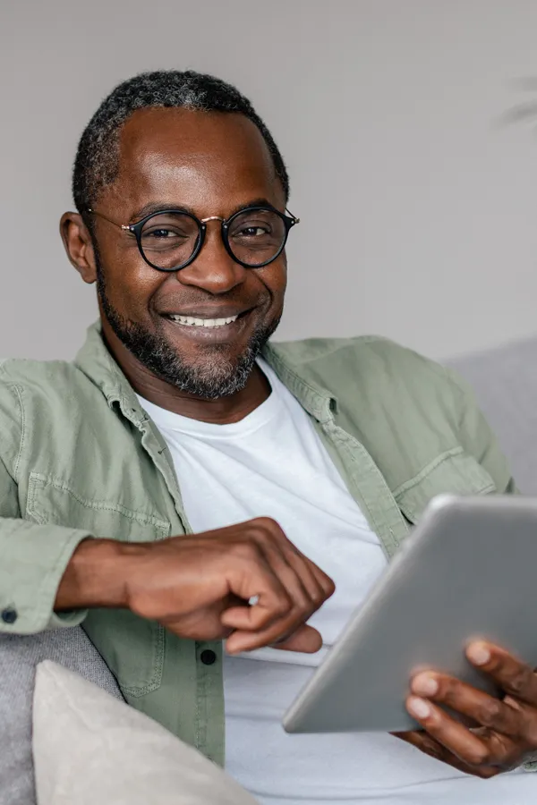 Micro-Current-Neurofeedback-Therapy-Treatment A middle-aged man working with a tablet on his couch. Get IASIS Microcurrent Neurofeedback Therapy from Discovery Health Healing Center in Green Bay.