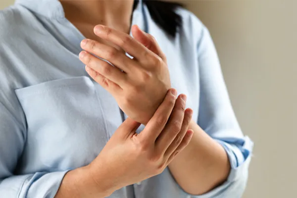 Rheumatoid-Arthritis-Clinic Close up of a woman in a blue blouse rubbing her wrist. Get rheumatoid arthritis treatment from Discovery Health Healing Center in Green Bay.