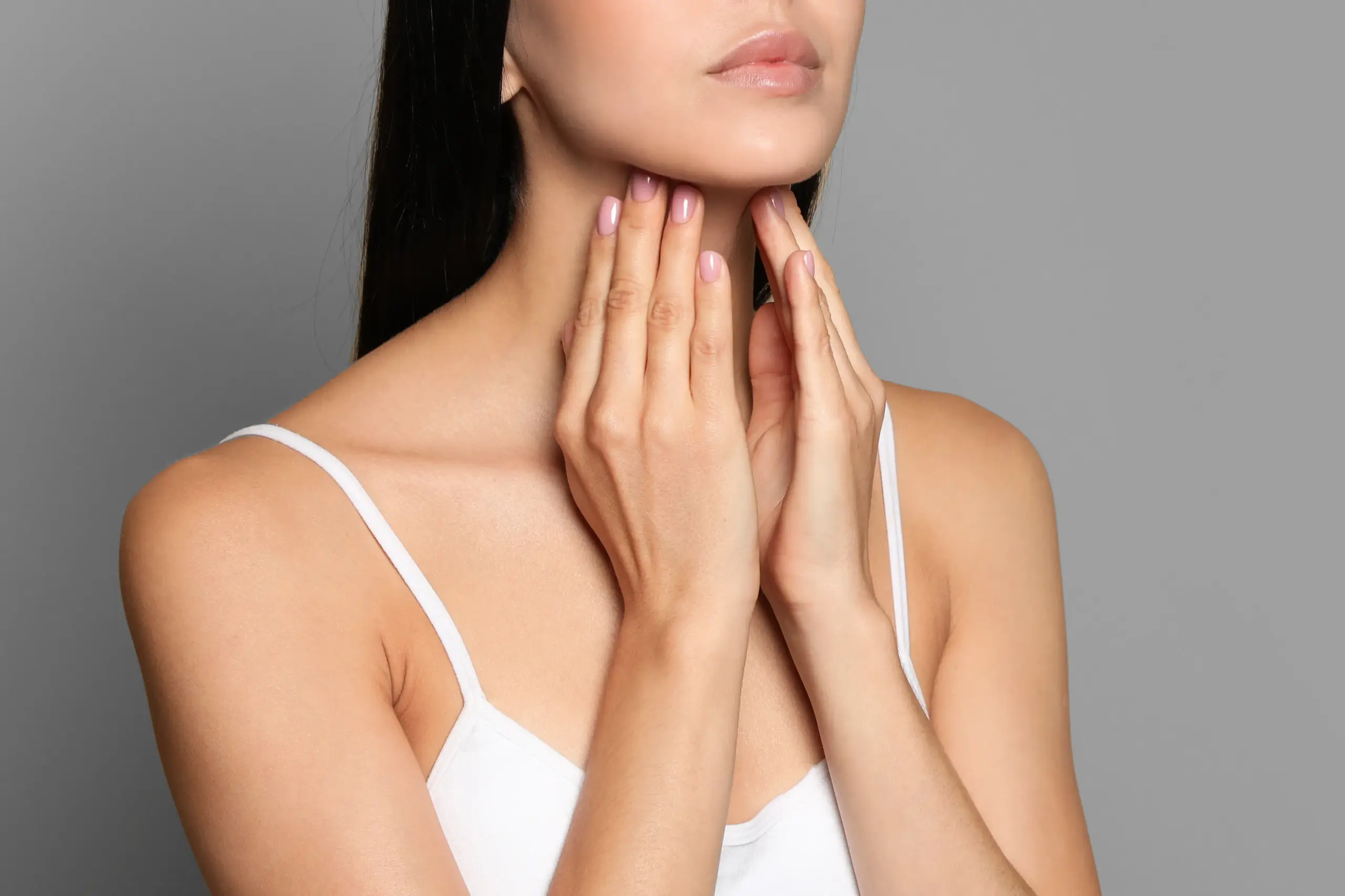 Thyroid-Doctor A woman in a white tank top touches her neck looking for signs of thyroid disorder. Get help for thyroid disorders from Discovery Health Healing Center in Green Bay.